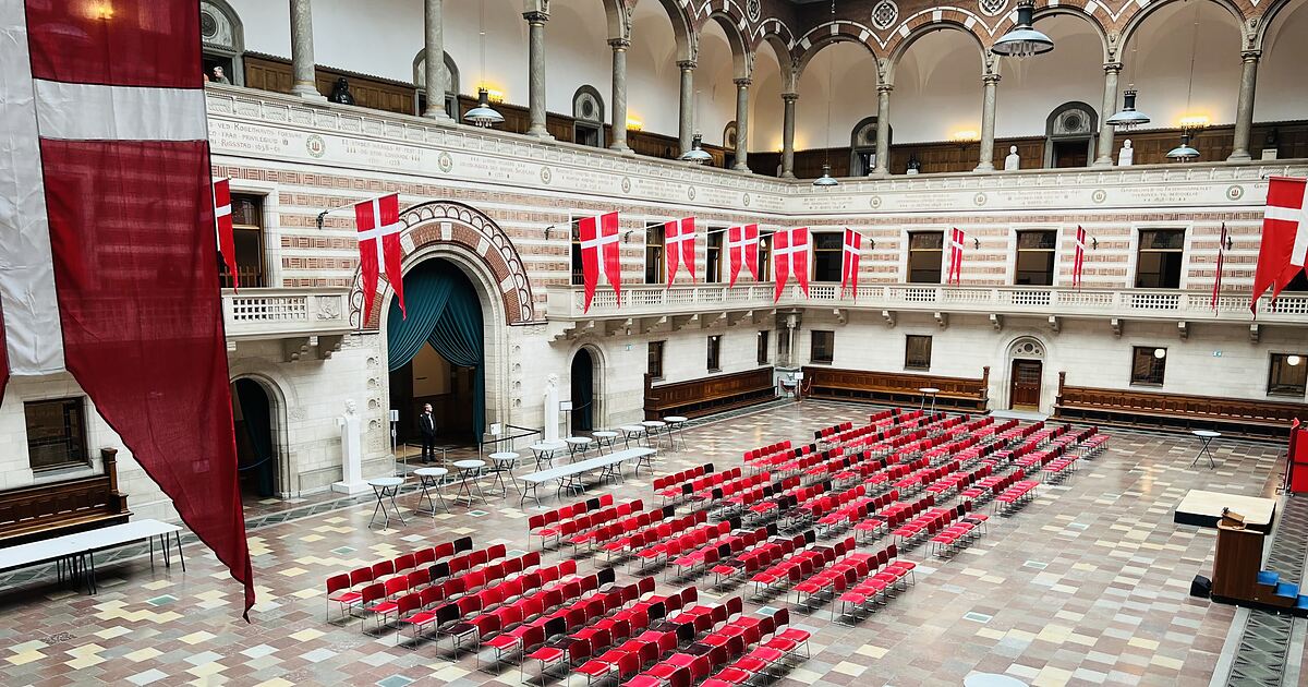 Rådhushallen på Københavns Rådhus gjort klar til grundlovsceremoni, med rækker af røde stole og Dannebrog langs væggene